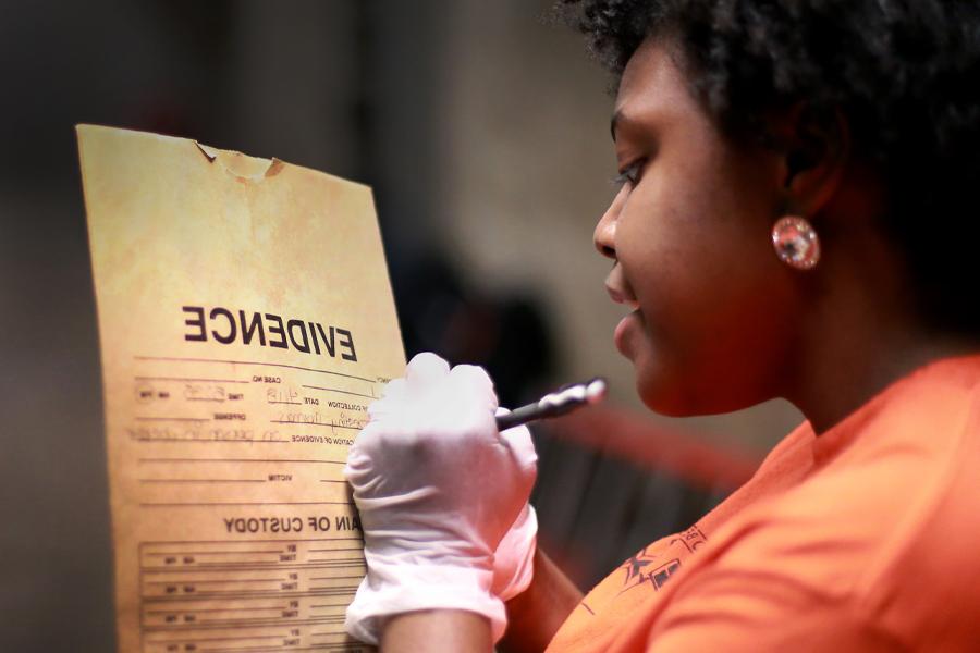 A student writes on an envelope marked "evidence".