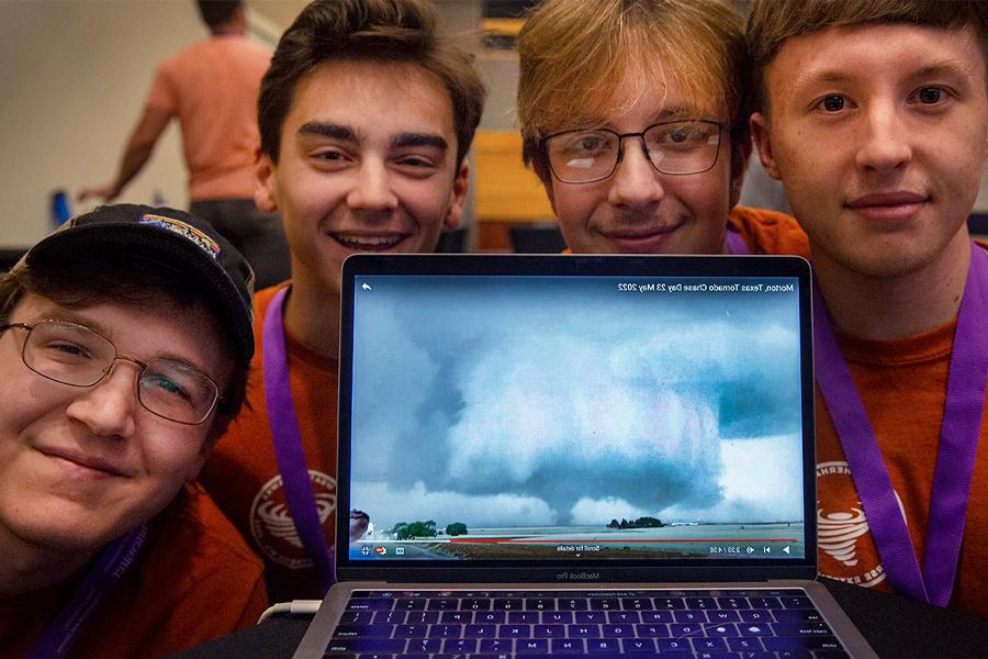 Students pose with a computer that shows stormy weather on the screen.