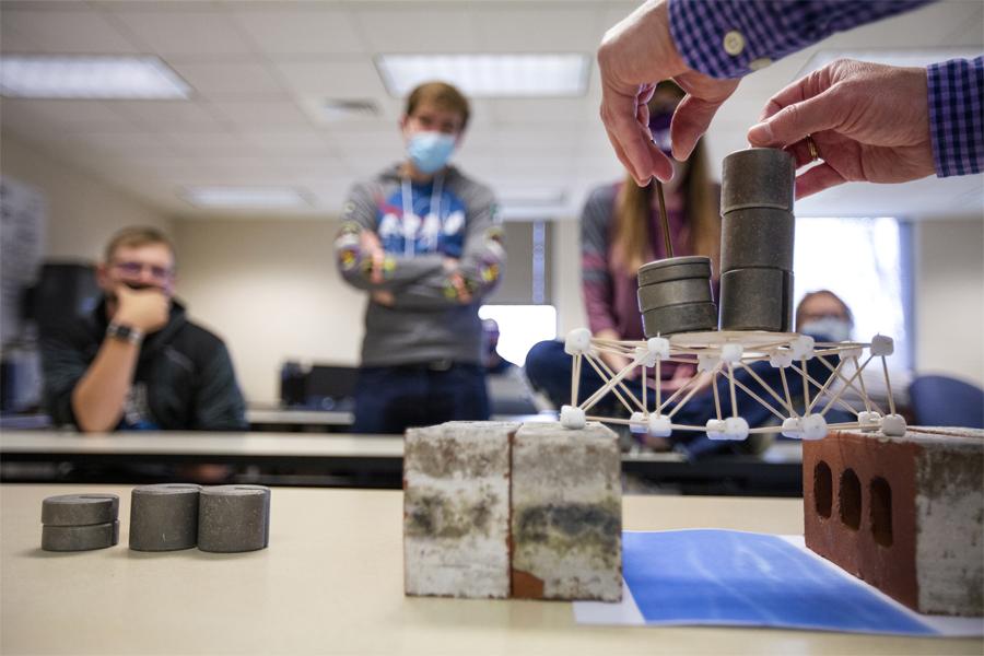 A class builds a bridge demonstration out of weights and toothpicks.