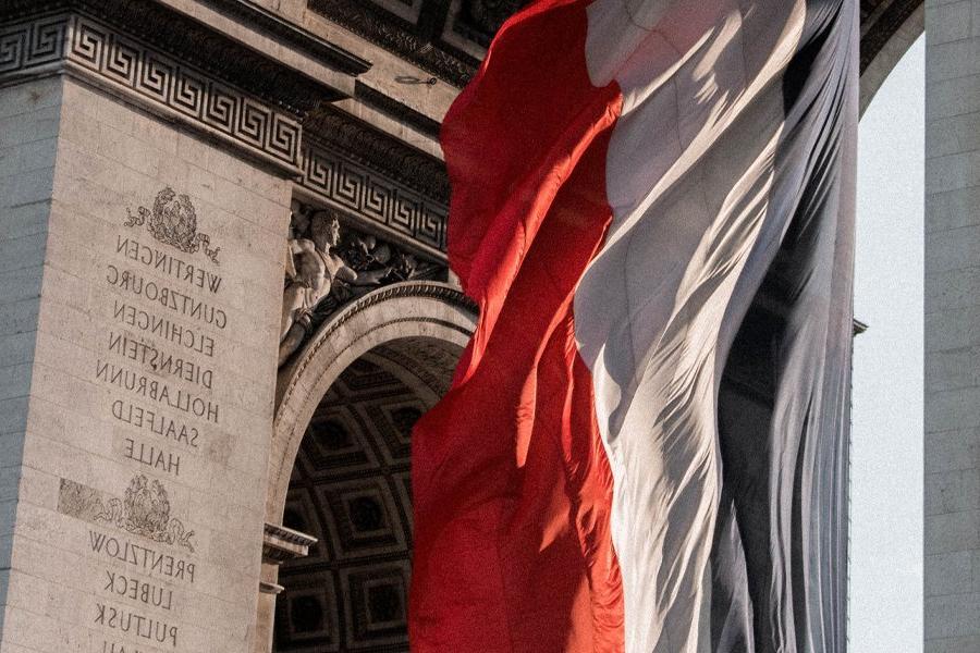 The French flag flies near the Arc de Triomphe.