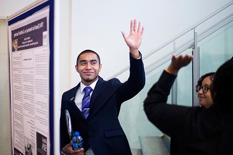 Finance student Miguel Miranda gets a high five from fellow McNair Scholar Jazmin Wilson, near his undergraduate research project on minority banks.