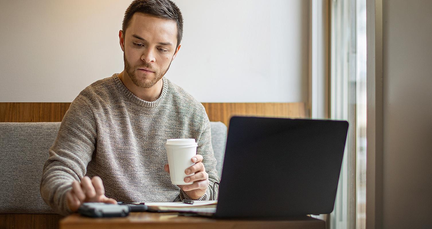 Man studying in cafe with laptop and textbook