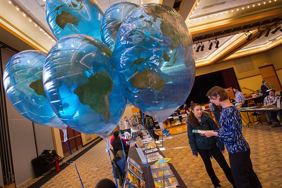 Two people talk in the Hamilton Room of the University Center with blue balloons in the foreground.