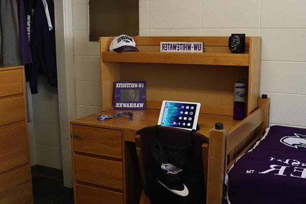 A desk with an iPad, a water bottle and a picture on top of it.