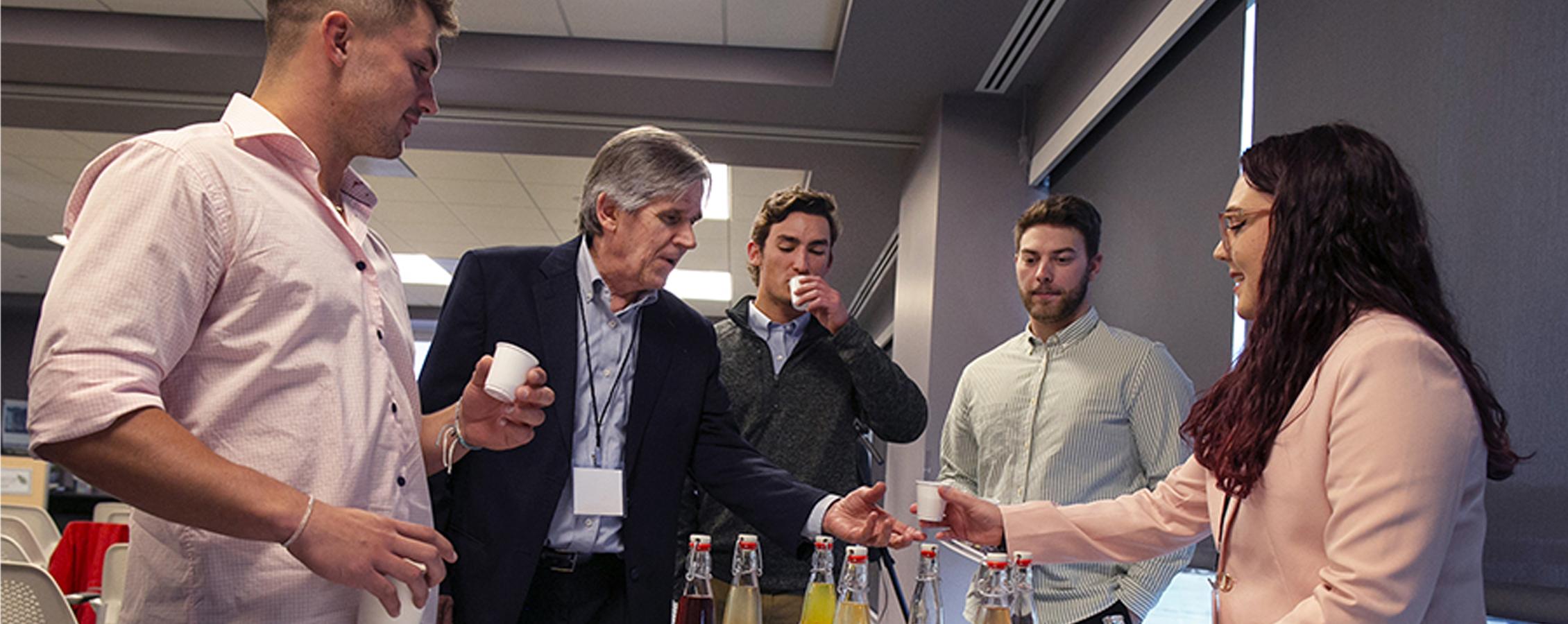 A student hands out small cups of kombucha.